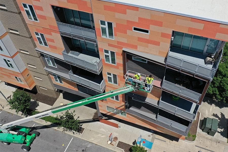 Crew working from a boom lift on the exterior facade and balconies of a multifamily apartment building