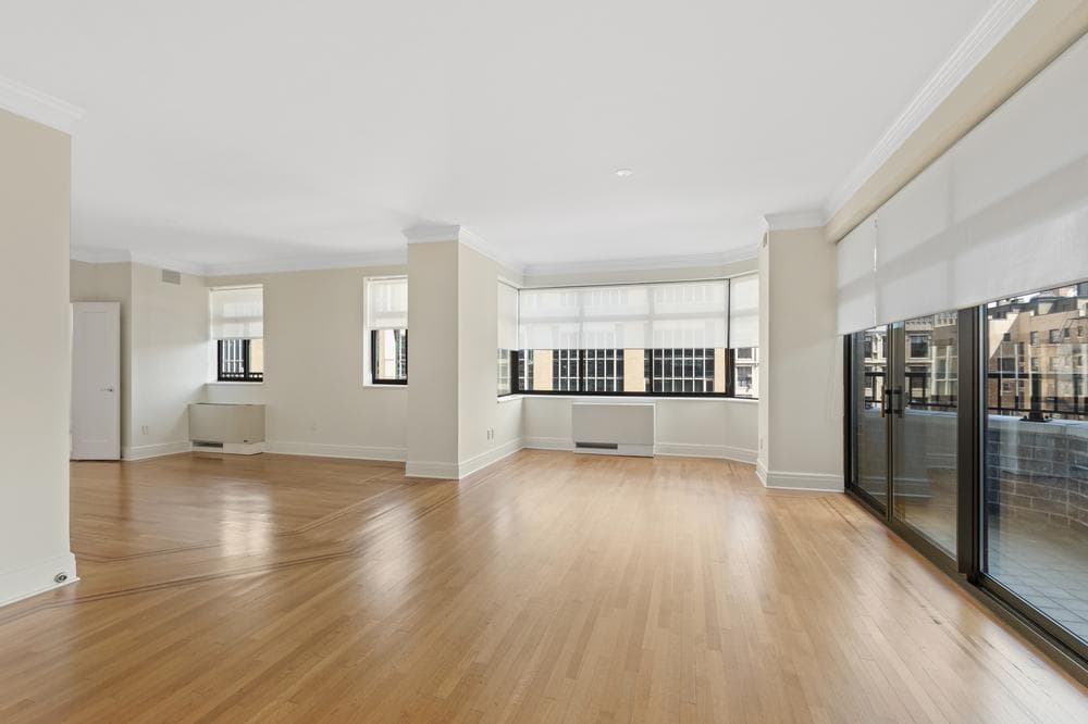 Empty two-bedroom apartment living and dining area with painted walls, crown molding and window trim
